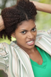Angry woman holding her curly hair in hands