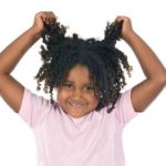 Young black girl pulling on her curly hair