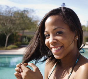 Pretty young woman happy on holiday with pool in background